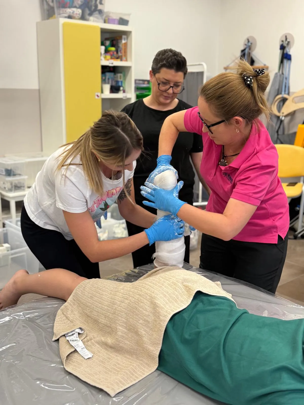 Dwie terapeutki modelują gips na nodze zgiętej w kolanie