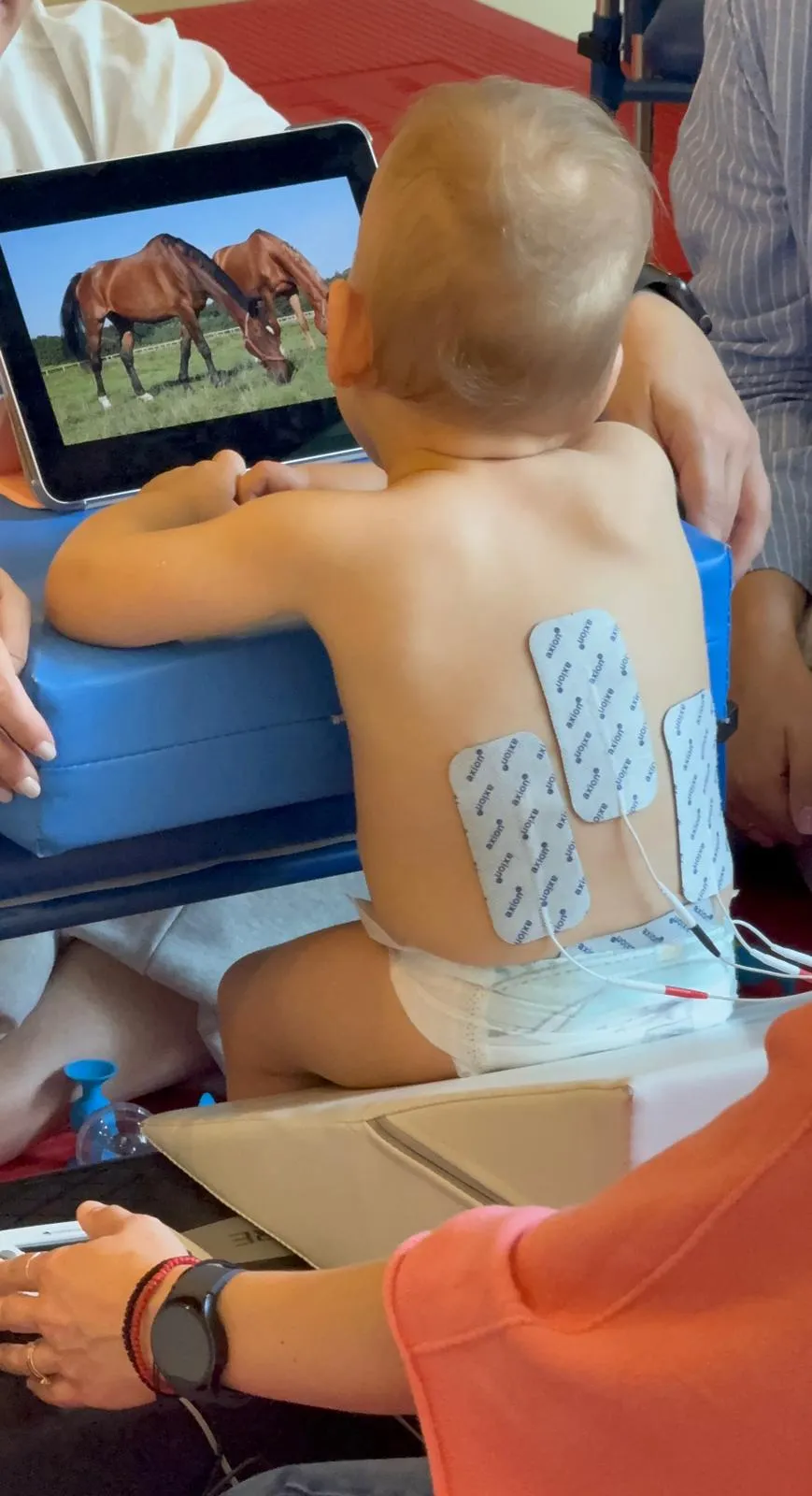 Maluch z elektrodami na plecach ogląda zdjęcia na tablecie